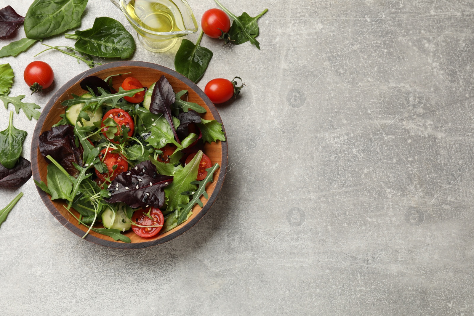 Photo of Tasty fresh vegetarian salad and ingredients on grey table, top view. Space for text