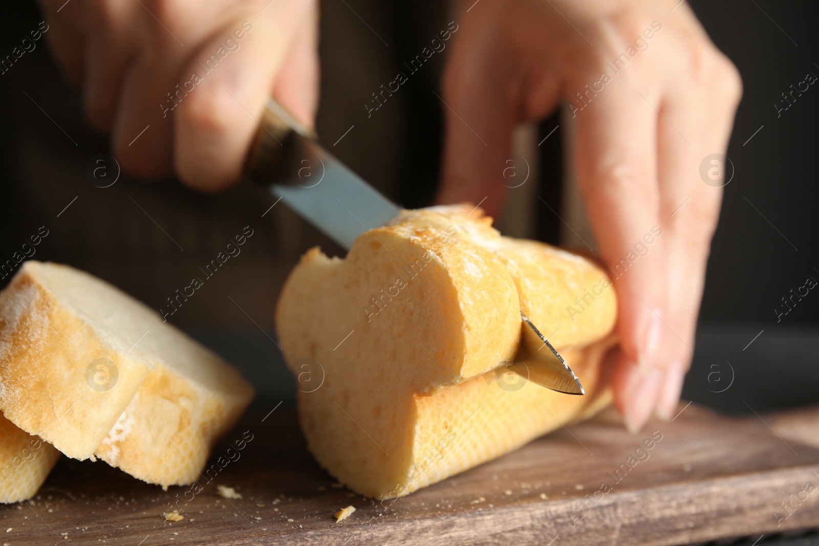 Photo of Woman cutting bread on wooden board, closeup