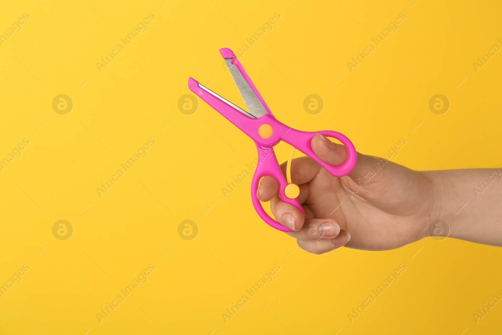 Photo of Woman holding small scissors on yellow background, closeup. Space for text