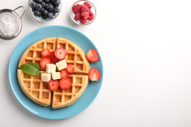 Tasty Belgian waffle with fresh berries, cheese and honey on white table, flat lay. Space for text