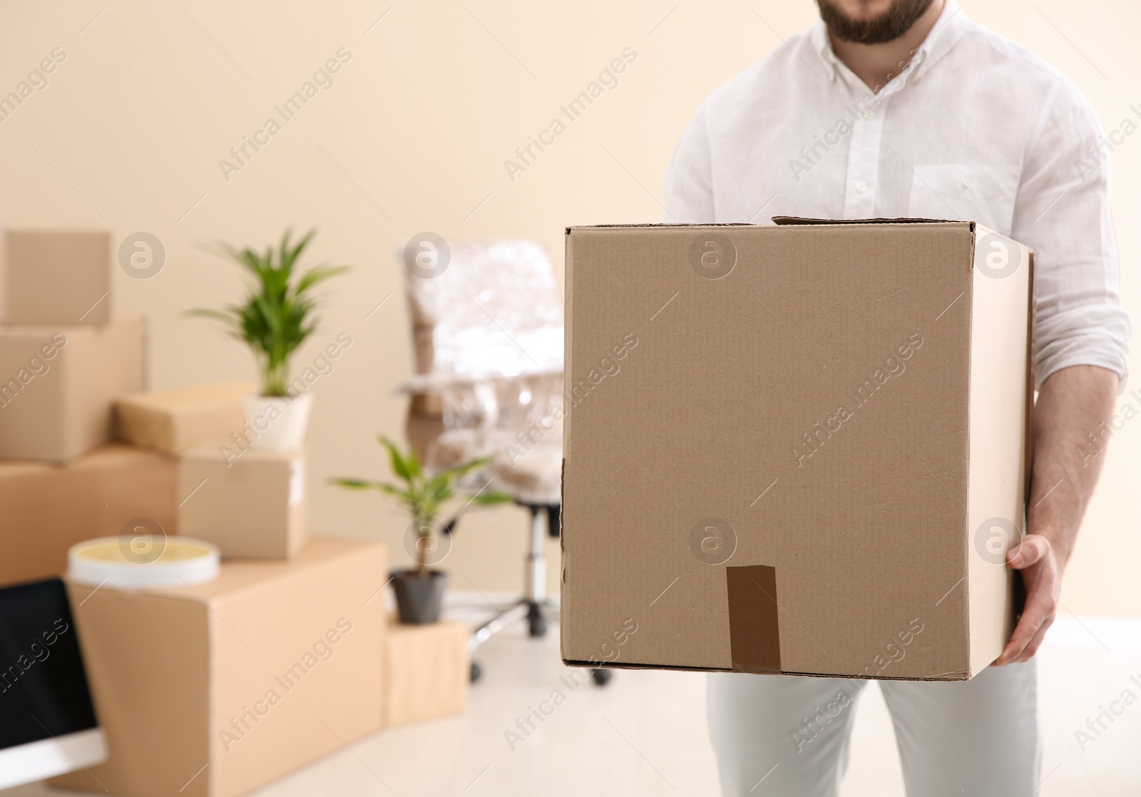 Photo of Man holding moving box in new office, closeup. Space for text