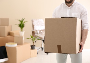 Man holding moving box in new office, closeup. Space for text