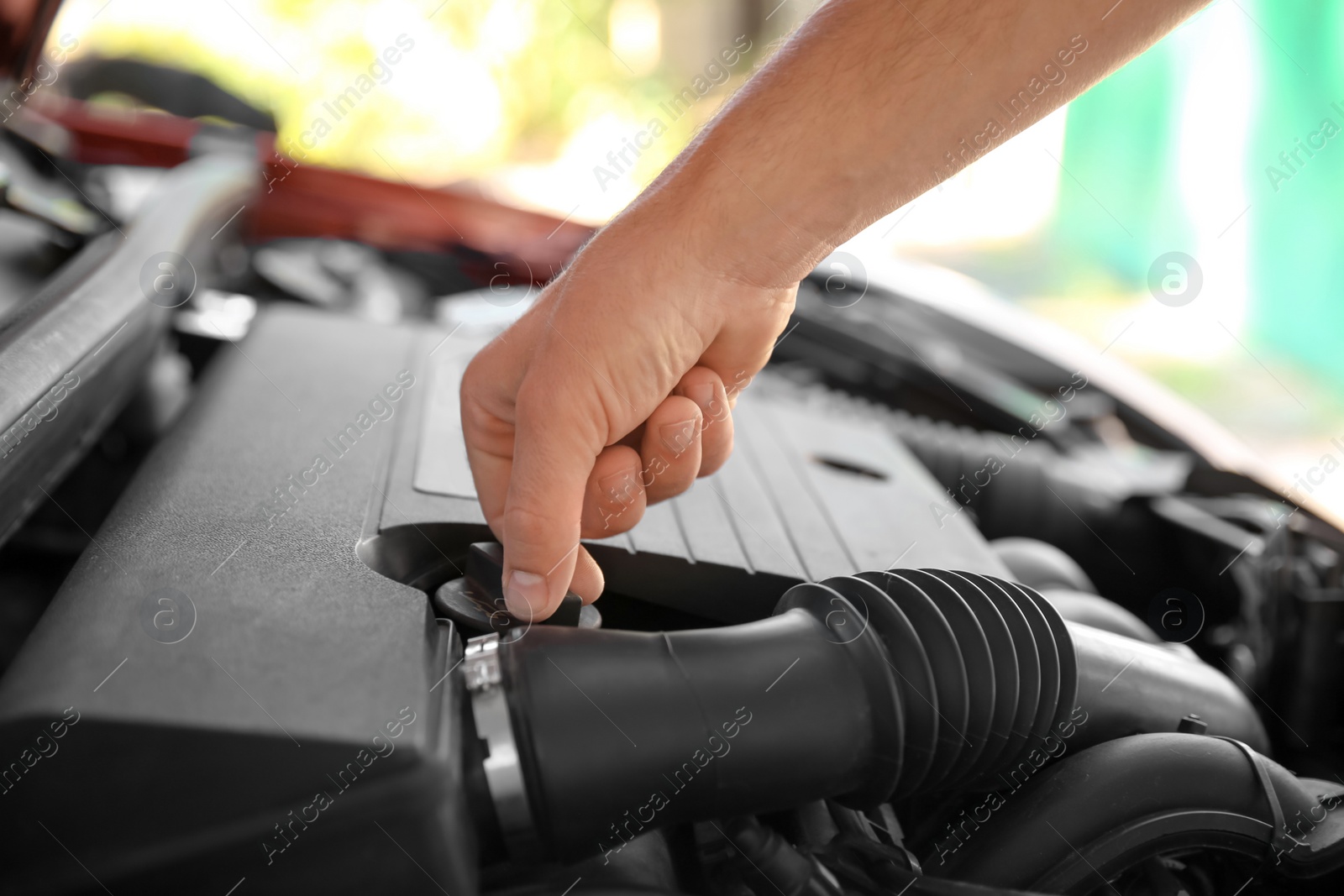 Photo of Mechanic opening engine oil filler cap, closeup