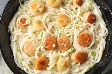 Photo of Delicious scallop pasta with green onion in pan, top view