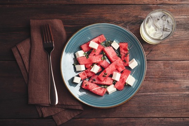 Photo of Delicious salad with watermelon and feta cheese on wooden table, flat lay