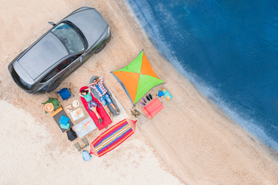Image of Couple with camping equipment near car on sand, aerial view. Summer trip