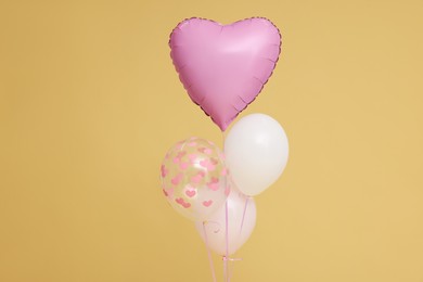 Photo of Bunch of heart and round shaped balloons for birthday party on beige background