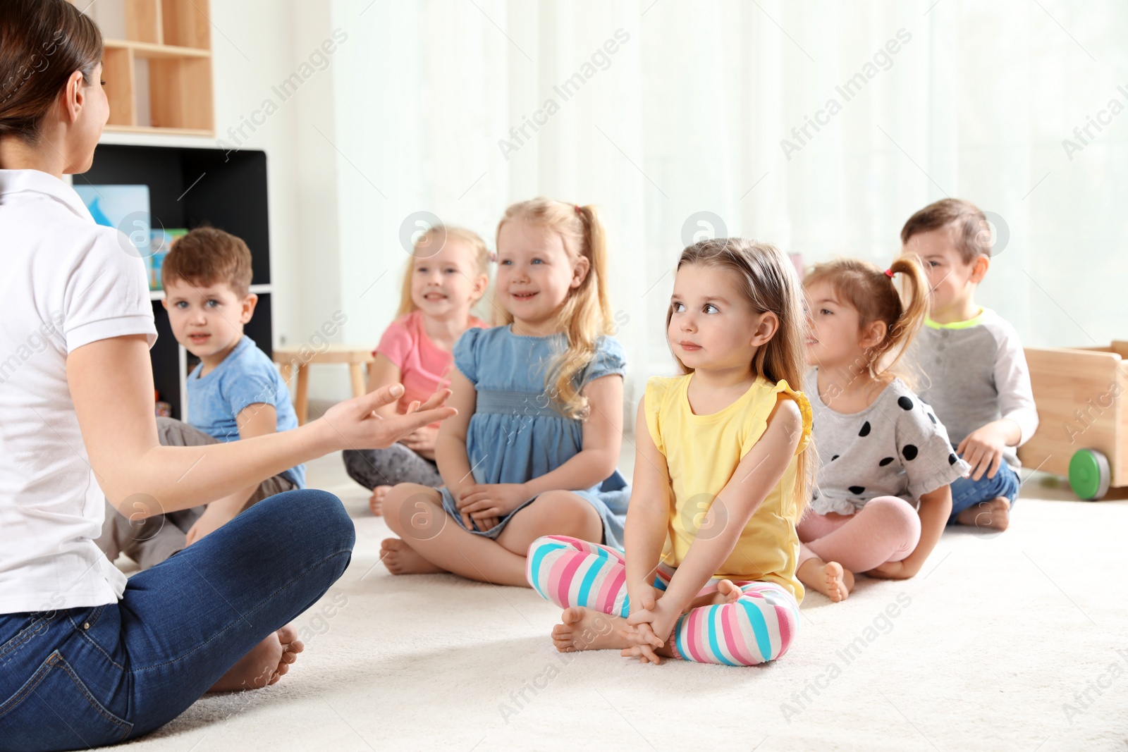 Photo of Kindergarten teacher and little children indoors. Learning and playing