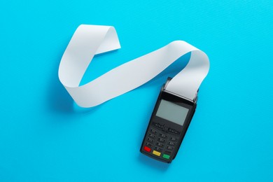 Payment terminal with thermal paper for receipt on light blue background, top view