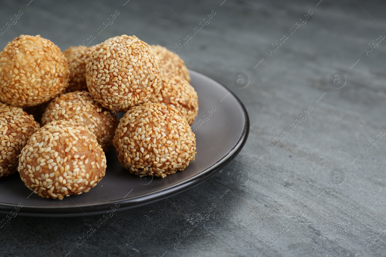 Photo of Many delicious sesame balls on grey table. Space for text