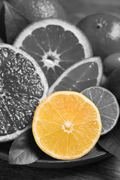 Fresh citrus fruits on plate, closeup. Black and white tone with selective color effect