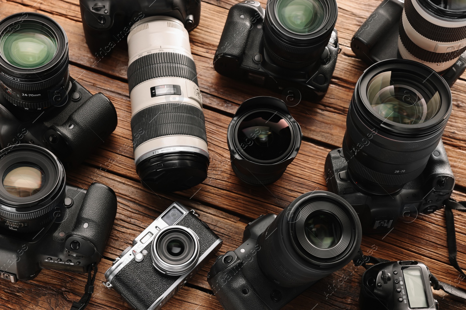 Photo of Modern cameras on wooden table, closeup. Professional photography equipment