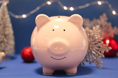 Photo of Composition with piggy bank and Christmas decor on color background