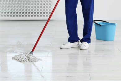 Man cleaning floor with mop indoors, closeup