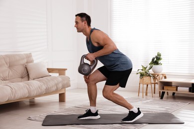 Photo of Muscular man training with kettlebell at home