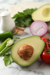 Photo of Fresh ingredients for guacamole on white marble table, closeup