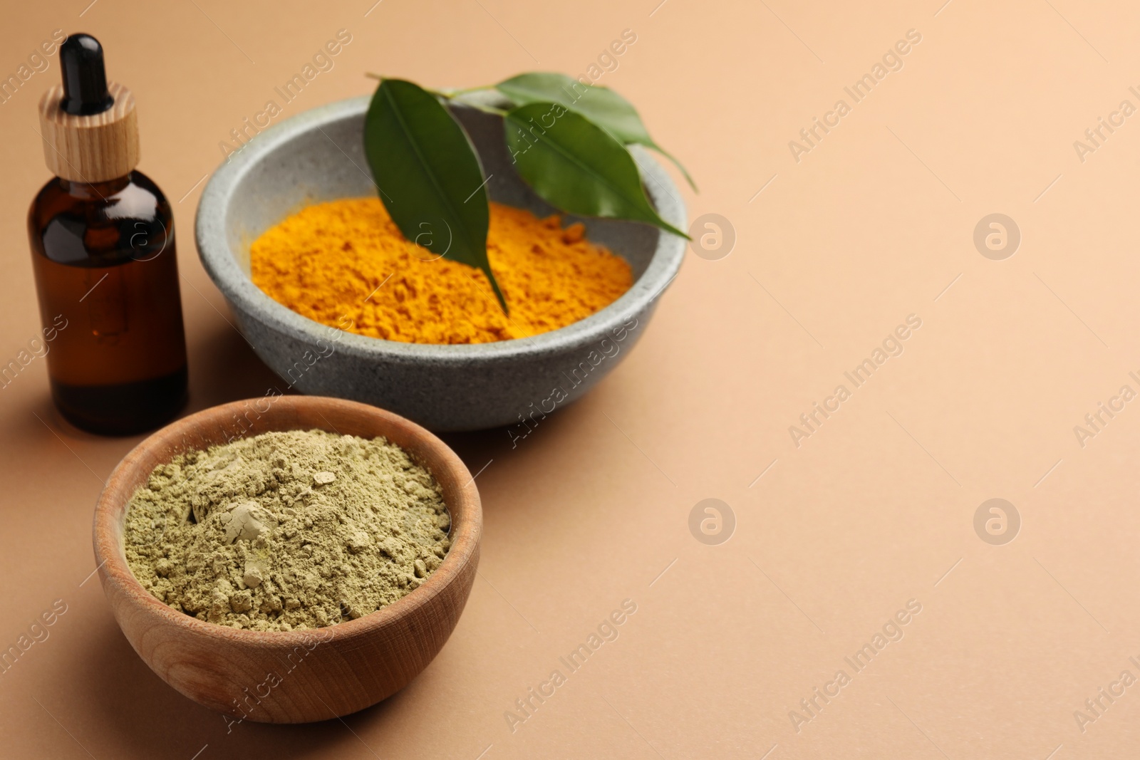 Photo of Bottle, henna and turmeric powder on coral background, space for text. Natural hair coloring