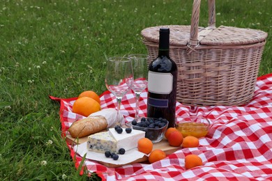 Picnic blanket with delicious food and wine outdoors on summer day