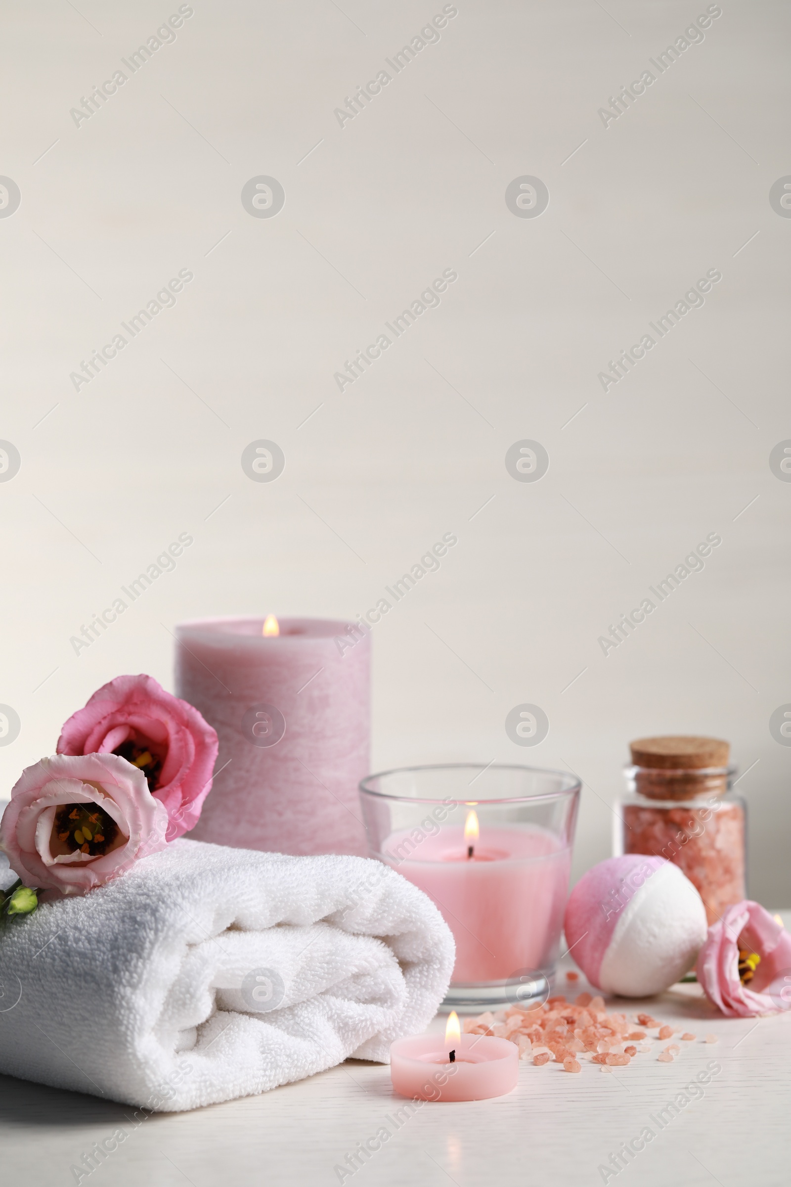 Photo of Beautiful composition with burning candles and different spa products on white table. Space for text