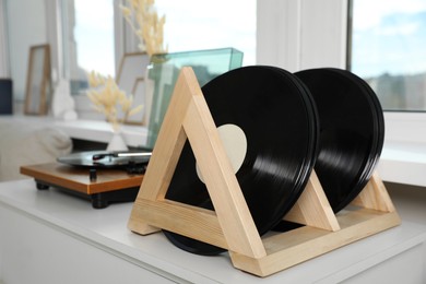 Photo of Vinyl records and player on white wooden drawer dresser indoors