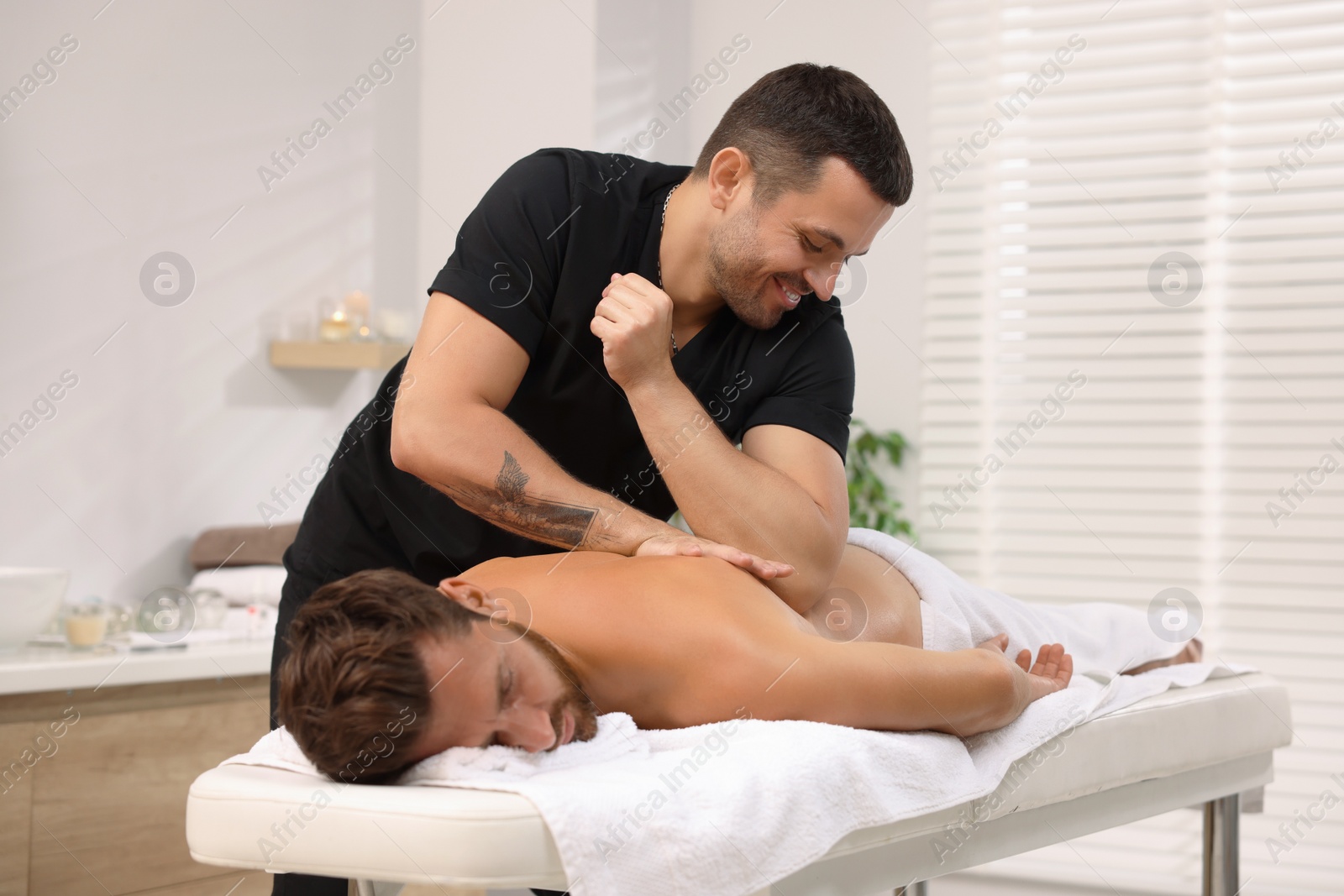 Photo of Man receiving professional back massage on couch in spa salon