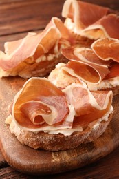 Photo of Board of tasty sandwiches with cured ham and cream cheese on table, closeup