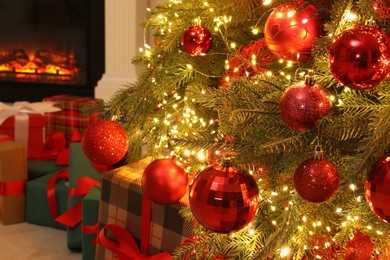 Many gift boxes under decorated Christmas tree and fireplace indoors