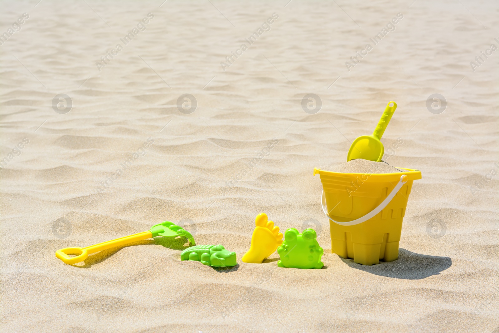 Photo of Set of colorful beach toys on sand. Space for text