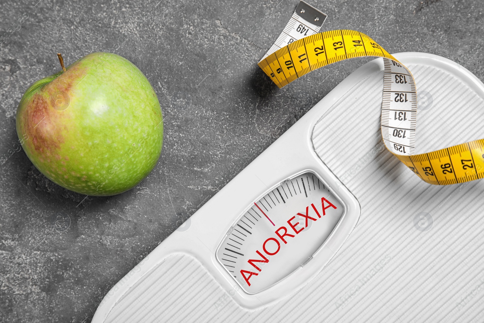 Image of Anorexia concept. Scales, measuring tape and apple on grey background, flat lay