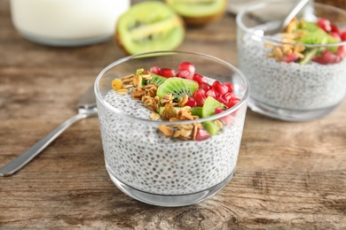 Photo of Dessert bowl of tasty chia seed pudding with granola, kiwi and pomegranate on table