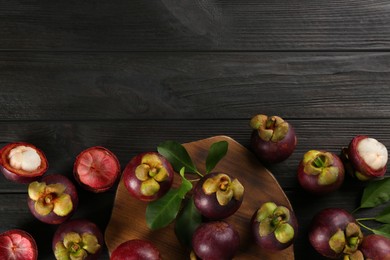 Fresh ripe mangosteen fruits on dark wooden table, flat lay. Space for text