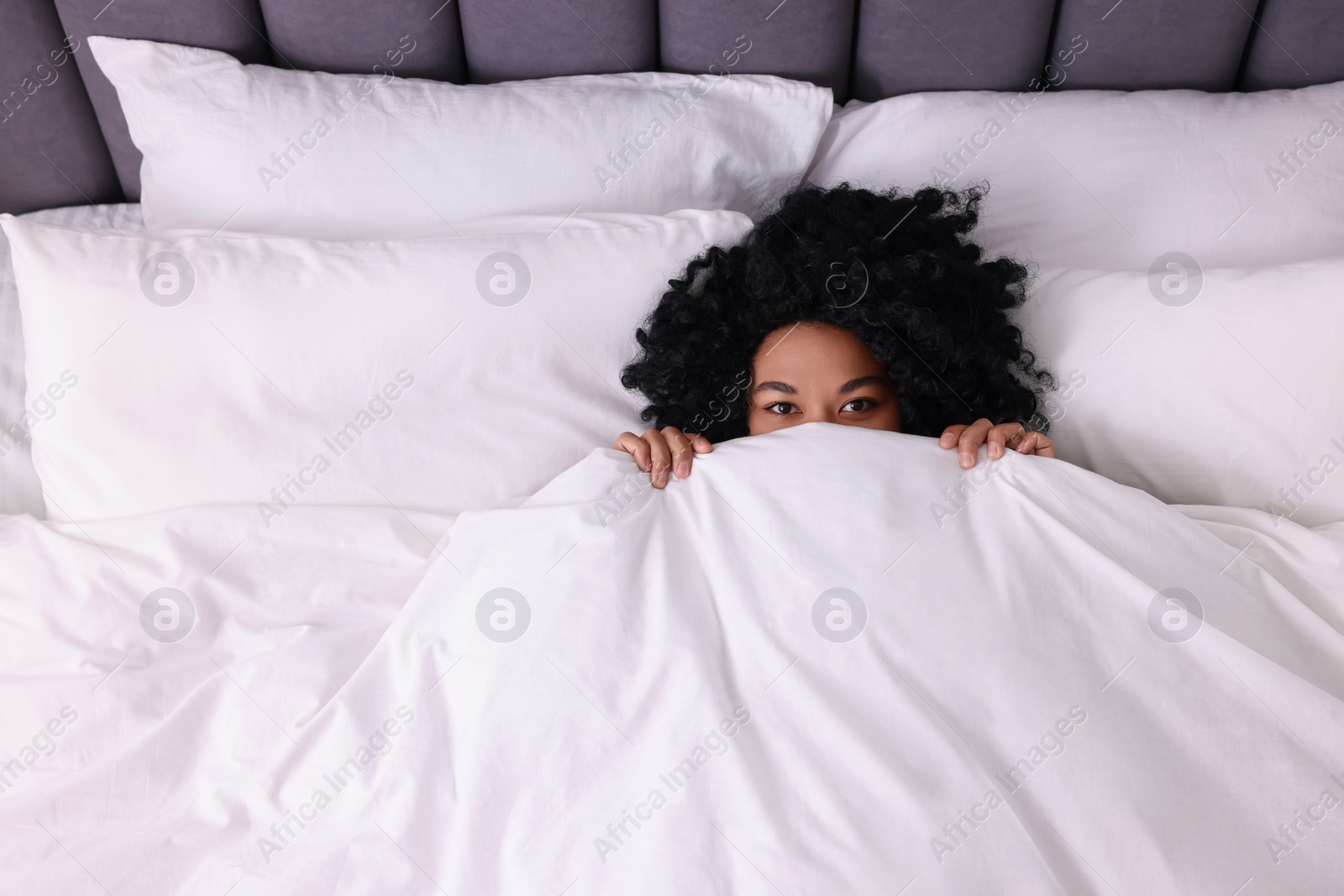 Photo of Young woman lying in soft bed at home, above view