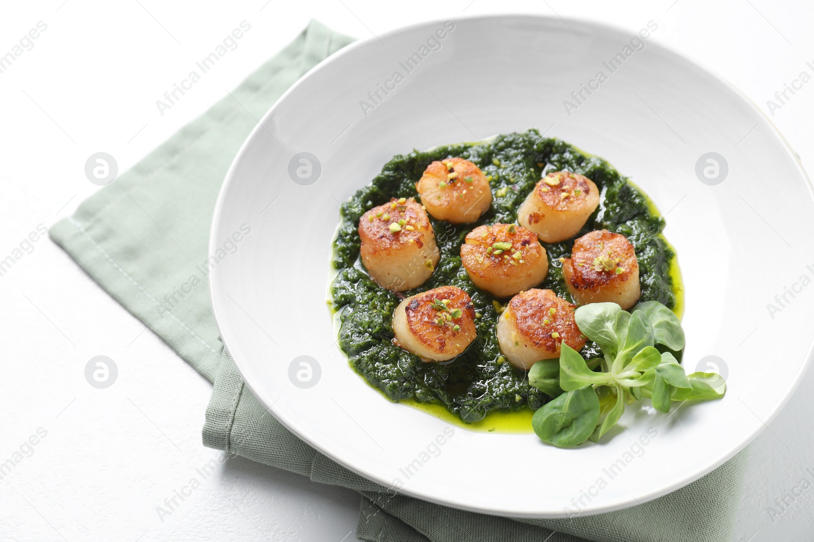 Photo of Delicious fried scallops with tasty sauce and corn salad in bowl on white table, closeup