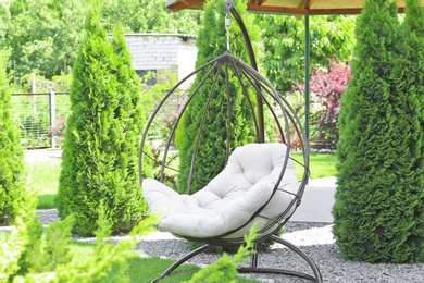 Beautiful English style garden with comfortable hanging chair on sunny day