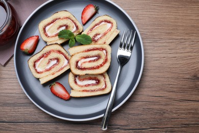 Photo of Tasty cake roll with strawberry jam and cream on wooden table, flat lay