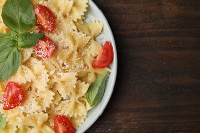 Photo of Tasty pasta with tomato, cheese and basil on wooden table, top view. Space for text