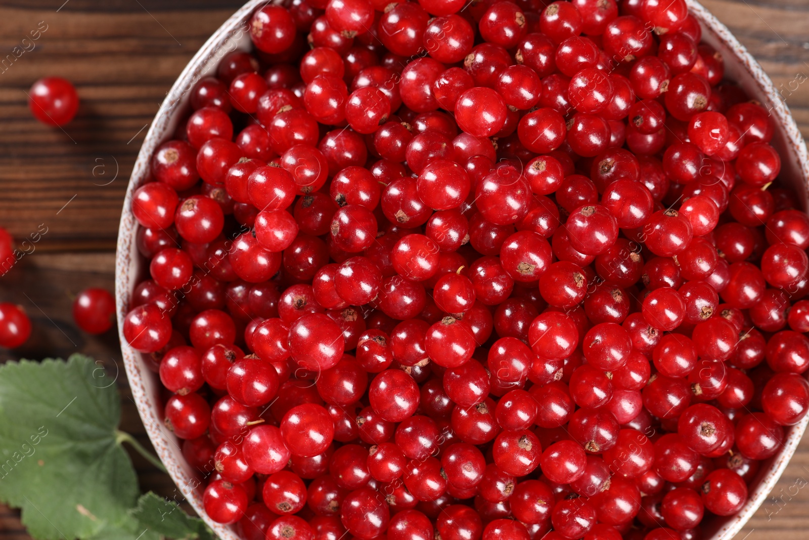 Photo of Ripe red currants and leaves on wooden table, flat lay