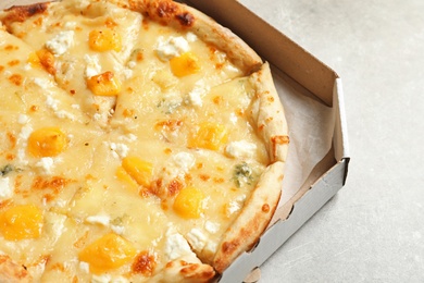 Photo of Carton box with cheese pizza on grey table, closeup. Food delivery service