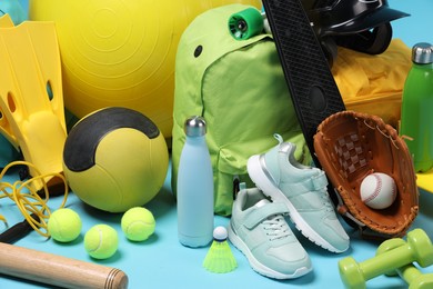 Many different sports equipment on light blue background, closeup