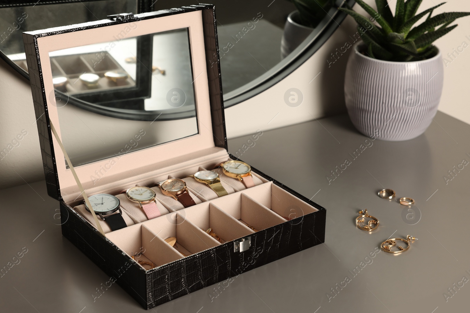 Photo of Elegant jewelry box with expensive wristwatches and beautiful bijouterie on grey table indoors