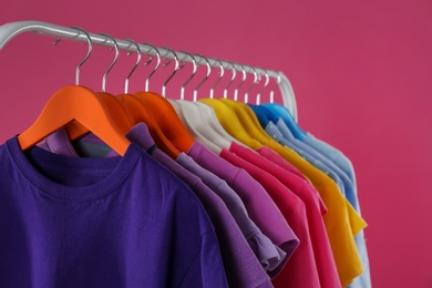 Photo of Rack with stylish children clothes on pink background, closeup