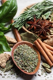 Different natural spices and herbs on wooden table, closeup