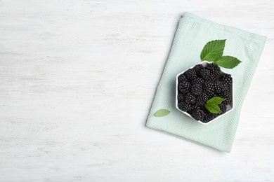 Photo of Flat lay composition with bowl of fresh blackberry and space for text on wooden background