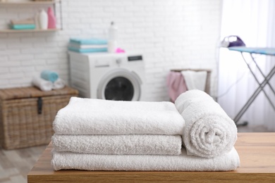 Photo of Soft bath towels on table against blurred background