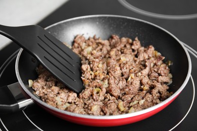 Frying minced meat in pan on induction stove, closeup