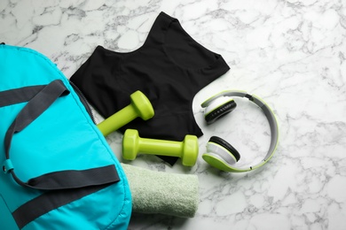 Flat lay composition with gym bag and sportswear on white marble table