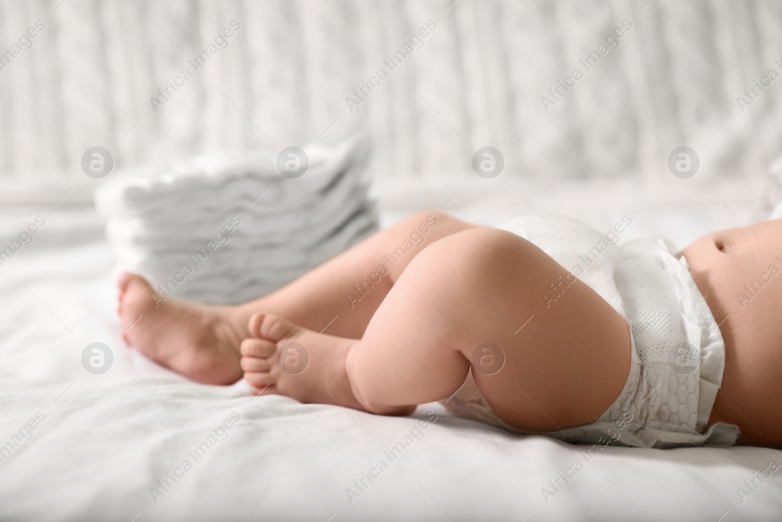 Photo of Little baby in diaper lying on bed, closeup