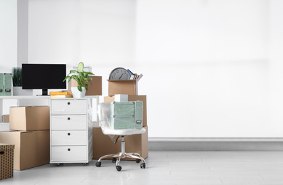 Cardboard boxes and packed belongings in office, space for text. Moving day