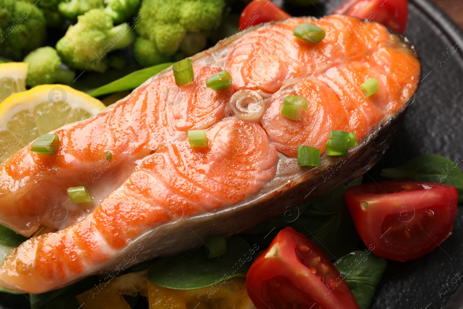 Photo of Healthy meal. Grilled salmon steak, green onion and vegetables on table, closeup