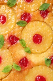 Tasty pineapple cake with cherries and mint as background, top view